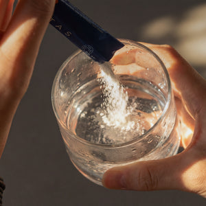 Cellitas supplement bottle beside glass of water on morning countertop